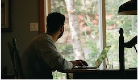 A person at a computer looking out the window.